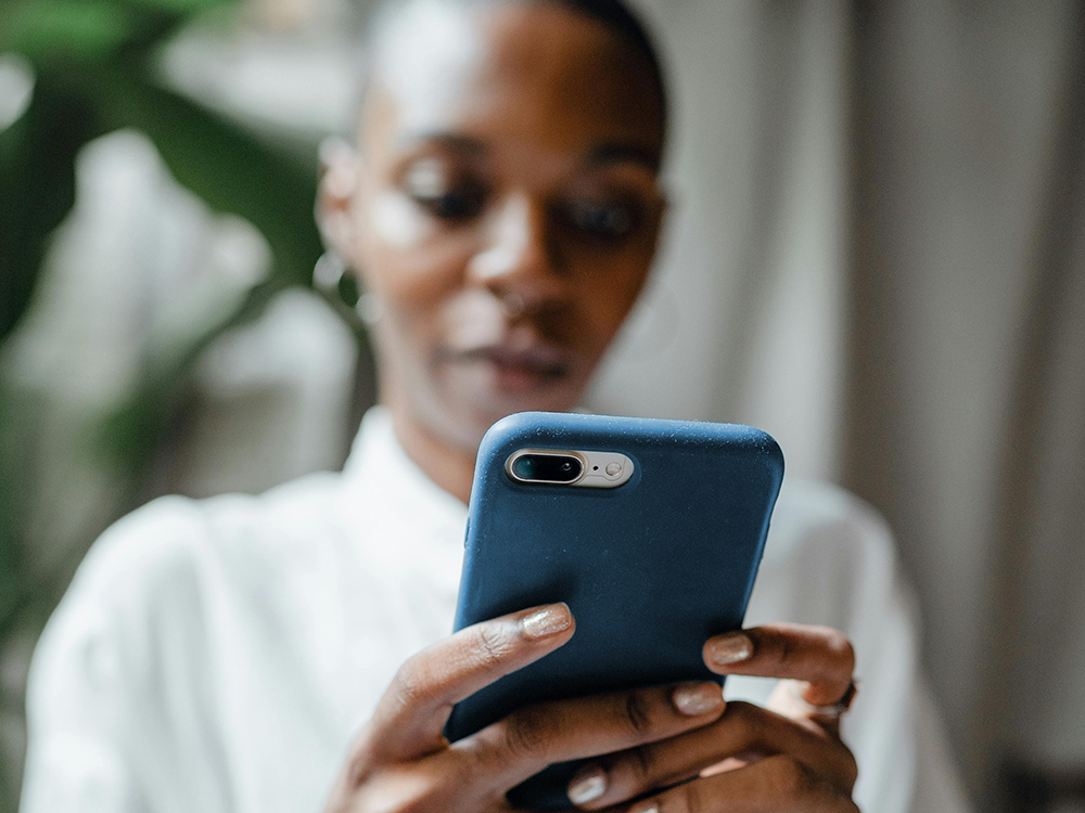 A woman in a white shirt looking at her cell phone