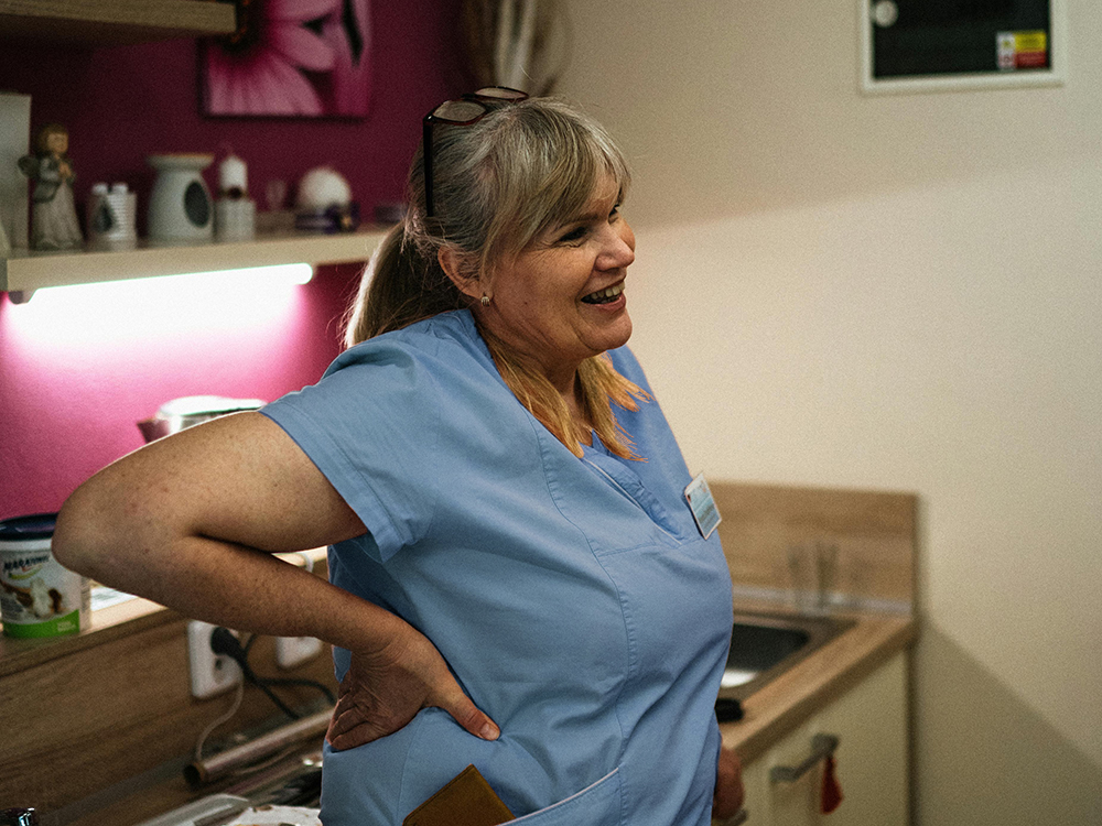 A middle-aged nurse leaning casually and smiling